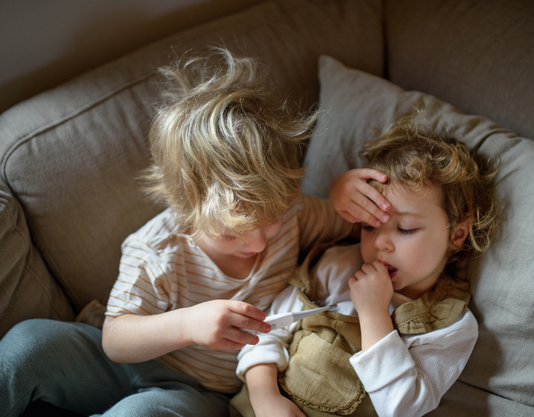 An image of two children, one helping the other has a temperature